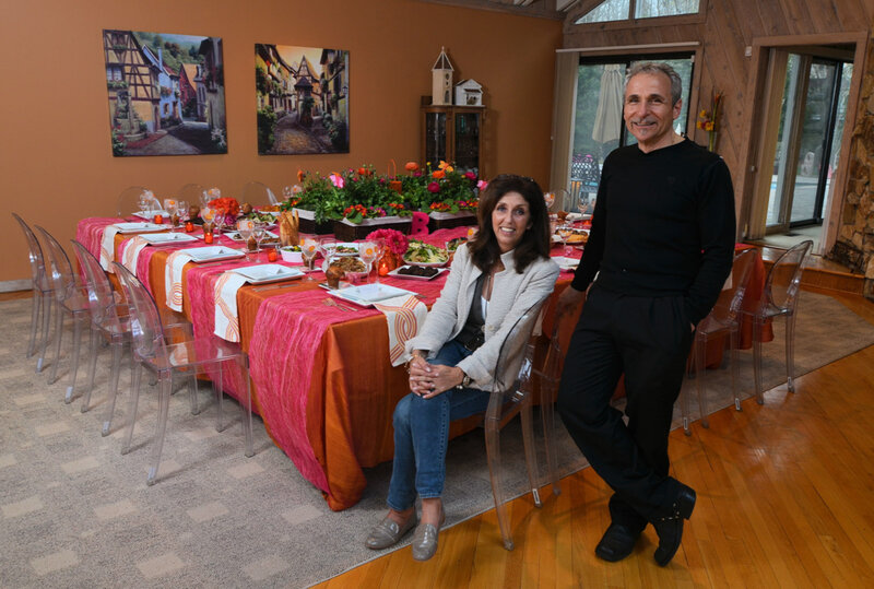 Chef Giorgio standing next to set table with orange table cloth