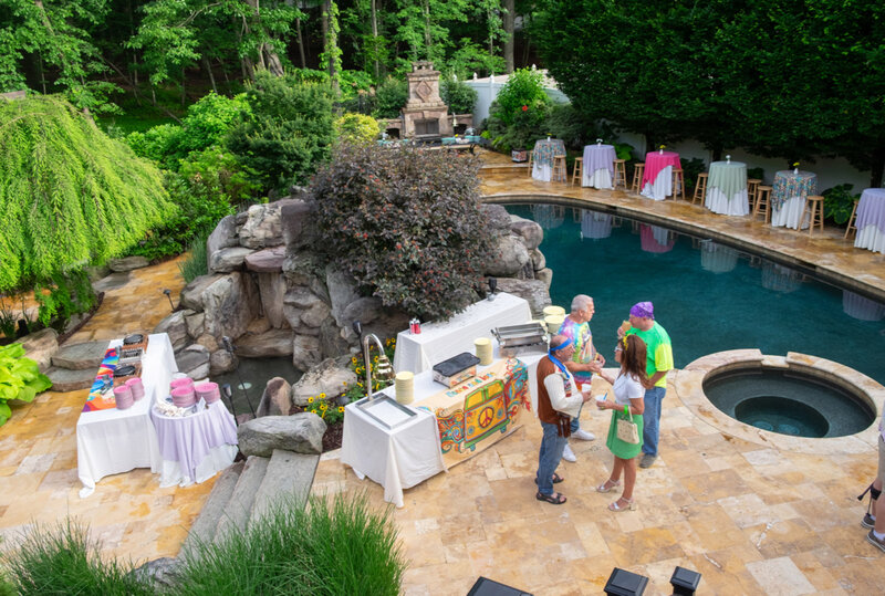 Party guests standing pool side near server tables